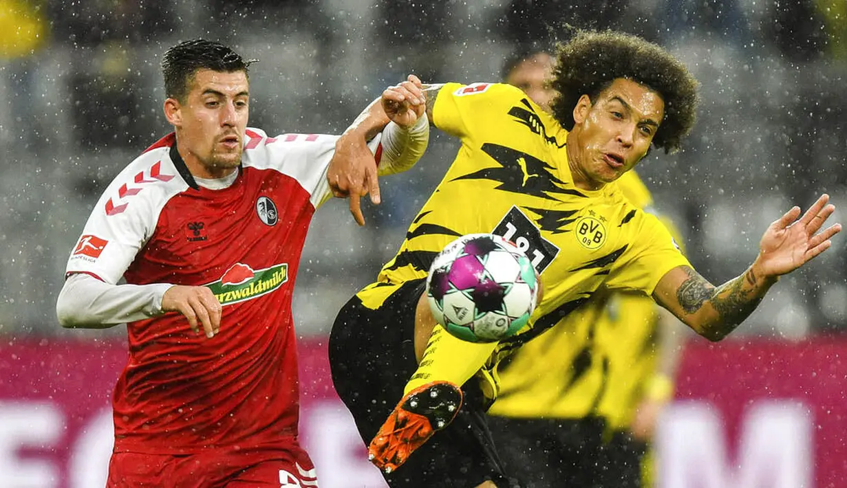 Gelandang Borussia Dortmund, Axel Witsel, berebut bola dengan pemain Freiburg, Baptiste Santamaria, pada laga Bundesliga di Signal Iduna Park, Sabtu (3/10/2020). Dortmund menang dengan skor 4-0. (AP Photo/Martin Meissner)
