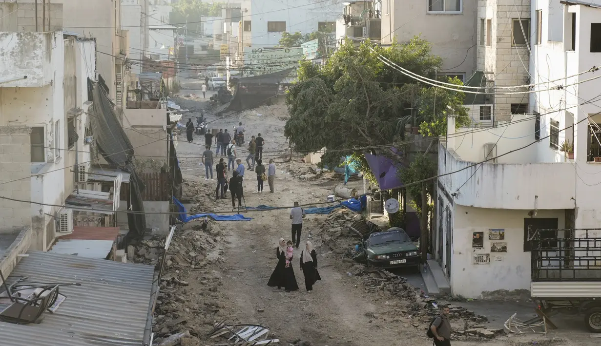 Warga Palestina berjalan di jalan yang rusak di kamp pengungsi Jenin di Tepi Barat, Rabu, 5 Juli 2023, setelah tentara Israel menarik pasukannya dari kubu militan. (AP Photo/Majdi Mohammed)