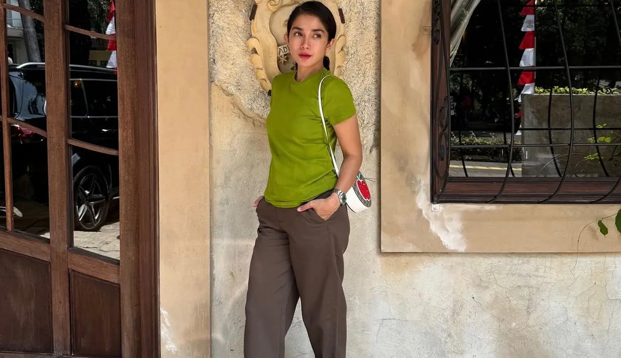 Lagi, penampilan santai Ussy dengan kaus hijau lengan pendek dan celana panjang cokelat, alas kaki putih gading, dan mini slig bag yang juga berwarna putih. [Foto: Instagram/ussypratama]