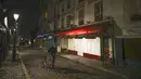 Seorang pria mendorong sepedanya di sepanjang deretan restoran yang tutup selama jam malam di Montmartre, Paris, Perancis, Selasa (15/12/2020). Pemerintah Perancis mencabut kebijakan lockdown terkait COVID-19 dan mulai memberlakukan jam malam. (AP Photo/Michel Euler)