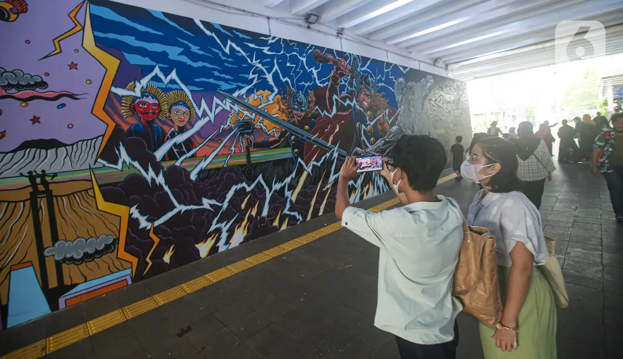 Warga mengambil gambar mural kolaborasi di Terowongan Kendal, Kawasan TOD Dukuh Atas, Jakarta, Rabu (6/7/2022). Disney Indonesia berkolaborasi bersama Jakarta Experience Board (JXB) dan Kita Art Friends menghadirkan karya seni mural terinspirasi dari film Marvel Studios "Thor: Love and Thunder." (Liputan6.com/Faizal Fanani)