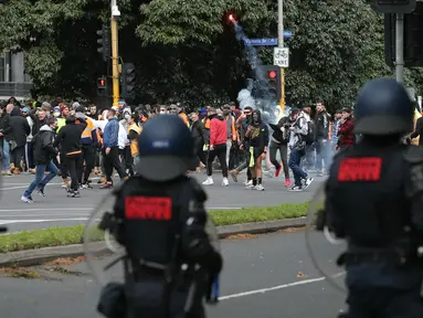 Seorang demonstran melemparkan suar saat protes terhadap peraturan Covid-19 di Melbourne (21/9/2021). Ribuan orang membuat kekacauan dan bentrok dengan polisi di kota dan mengambil alih jalan raya utama Melbourne saat protes terjadi. (AFP/STR)