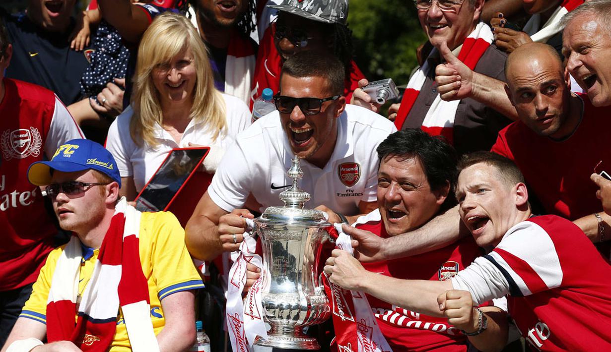 Lukas Podolski (tengah) berfoto bersama para suporter fanatik "The Gunners" sambil memegang trofi Piala FA saat parade kemenangan di London, Inggris, (18/5/2014). (REUTERS/Andrew Winning)