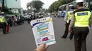 Petugas Dinas Perhubungan menunjukkan selebaran sosialisasi pemberlakuan sistem ganjil genap di pintu masuk Gardu Tol Cibubur 2, Jakarta, Senin (16/4). Aturan ini berlaku untuk kendaraan pribadi atau golongan I dan II. (Liputan6.com/Faizal Fanani)