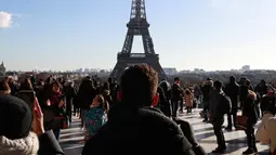 Sejumlah orang melihat aksi menegangkan seniman trapeze, Nathan Paulin berjalan di seutas tali dari Menara Eiffel menuju alun-alun Trocadero, Paris, 9 Desember 2017. Pria 22 tahun itu melakukan penyeberangan sejauh 2.198 kaki. (JACQUES DEMARTHON/AFP)