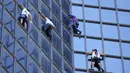 Pendaki Alain Robert (kedua kanan) atau Spiderman Prancis bersama Marcin Banot, Alexis Landot, dan Leo Urban memanjat Menara Total di La Defense, Paris, Prancis, 7 September 2021. Alain dengan tangan kosong memanjat menara setinggi 190 meter itu untuk menentang izin kesehatan. (THOMAS SAMSON/AFP)