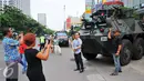 Sejumlah warga  melakukan selfie dengan latar belakang panser Anoa milik TNI di LTC Glodok, Jakarta, Jumat (4/11). Pengamanan ini merupakan bentuk kerja sama antara TNI-Polri dalam menjaga keamanan terkait demo bela islam . (Liputan6.com/Angga Yuniar)