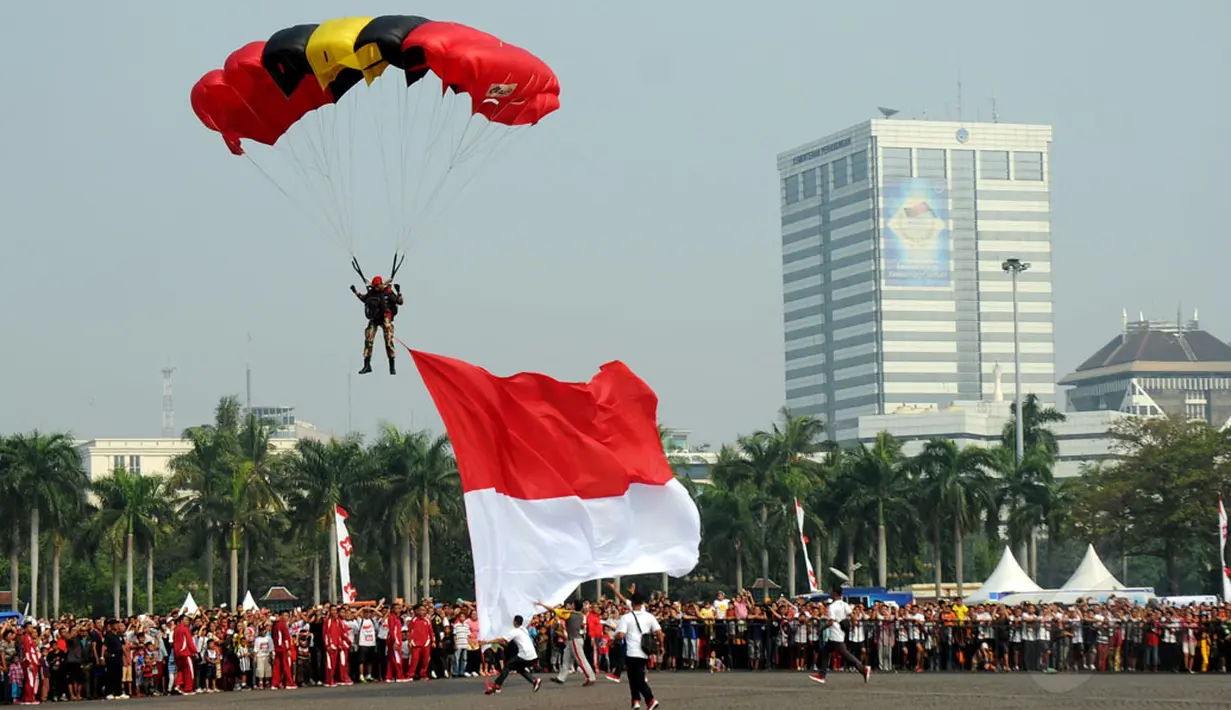 Dengan membawa Sang Merah Putih berukuran besar, salah satu peterjun bersiap mendarat di kawasan Tugu Monas, Jakarta, (31/8/2014). (Liputan6.com/Helmi Fithriansyah)