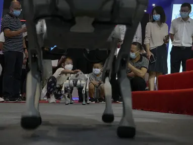 Anak-anak yang memakai masker wajah bermain dengan robot side-follow cerdas Unitree Go 1 selama Konferensi Robot Dunia di Pusat Konferensi dan Pameran Internasional Yichuang di Beijing, Kamis (18/8/2022). (AP Photo/Andy Wong)