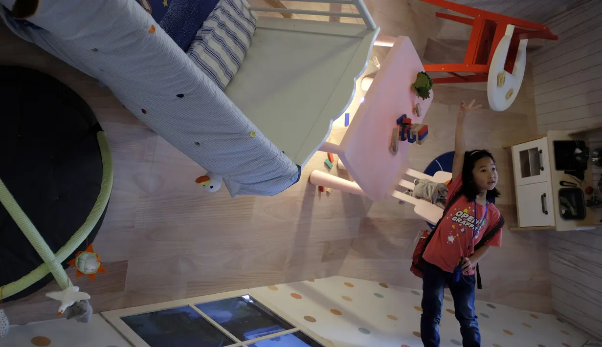 Seorang anak berpose saat berada di salah satu ruangan di rumah terbalik di Huashan Creative Park, Taipei, Taiwan, Selasa (8/3/2016). Rumah yang dibangun selama dua minggu dengan biaya USD 600 ribu atau 8 miliar itu menarik banyak wisatawan. (SAM YEH/AFP)