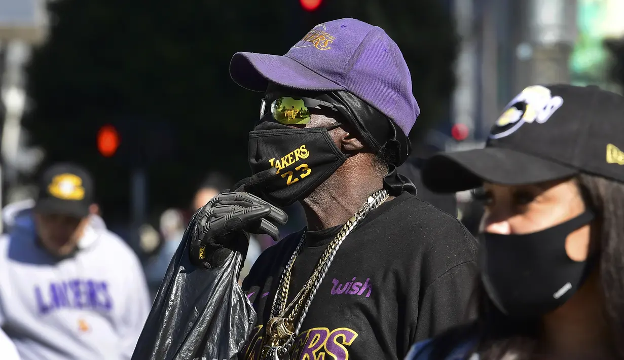 Dua orang fans berdiri di depan tugu peringatan di dekat Staples Center, Los Angeles, California, Selasa (26/1/2021) untuk mengenang 1 tahun meninggalnya bintang LA Lakers, Kobe Bryant bersama putrinya, Gianna dalam sebuah tragedi kecelakaan helikopter. (AFP/Frederic J. Brown)