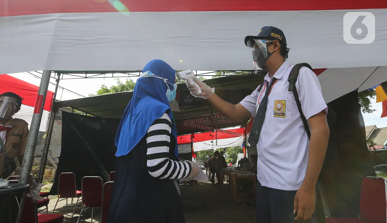 Petugas KPPS berseragam sekolah mengecek suhu tubuh warga pada Pilkada Tangsel di TPS 49 Cendana Residence, Pondok Benda, Pamulang, Rabu (9/12/2020). TPS yang mengusung Rindu Sekolah Lagi (Kisah-Kasih di Sekolah) terapkan protokol kesehatan pada Pilkada Serentak 2020. (Liputan6.com/Fery Pradolo)
