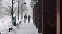 Orang-orang berjalan saat terjadi badai salju di lingkungan East Village, Des Moines, Iowa, pada tanggal 12 Januari 2024. (Christian MONTERROSA/AFP)