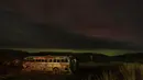 Sebuah aurora borealis, juga dikenal sebagai cahaya utara, terlihat di langit malam saat awan bergerak di atas tengara pinggir jalan yang dikenal sebagai "That NW Bus" di Washtucna, Washington, Amerika Serikat, 27 Februari 2023 dini hari. Berdenyut dalam garis-garis merah, hijau, dan ungu, aurora – juga dikenal sebagai cahaya utara – tampil semarak di belahan bumi utara dari Minggu malam hingga Senin pagi. (AP Photo/Ted S. Warren)