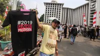 Pedagang menjual kaos #2019GantiPresiden di halaman Masjid Istiqlal, Jakarta, Jumat (10/8). Mereka memanfaatkan peluang berdagang usai deklarasi Capres dan Cawapres. (Liputan6.com/Fery Pradolo)