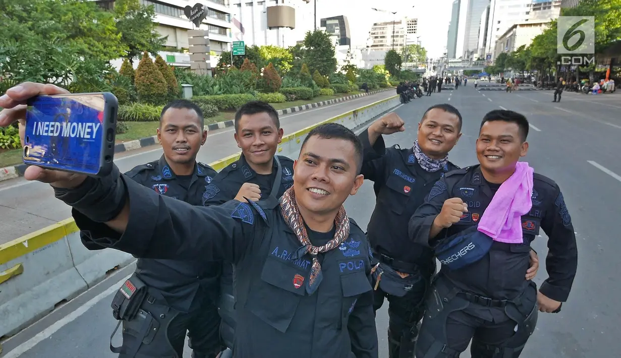 Sejumlah Korps Brimob berswafoto disela penjagaan mereka di kawasan MH Thamrin, Jakarta, Jumat (24/5/2019). Usai kerusuhan 22 Mei 2019, penjagaan di kawasan jalan MH Thamrin sampai Jumat, 24 Mei 2019 masih terus dilakukan oleh aparat kepolisian. (Liputan6.com/Herman Zakharia)