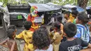 Relawan pekerja sosial, Ashok Kurmi mengajarkan anak-anak cara mengikuti protokol kesehatan di daerah kumuh Mumbai pada 2 Juni 2021. Kurmi turun tangan memerangi virus Corona COVID-19 di daerah kumuh Mumbai menggunakan aksesori yang tidak biasa, yaitu kostum badut. (INDRANIL MUKHERJEE/AFP)