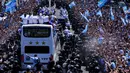Pemain Timnas Argentina memamerkan trofi Piala Dunia 2022 dari bus saat parade kemenangan di Buenos Aires, Argentina, 20 Desember 2022. Jutaan orang menyambut kepulangan Lionel Messi dan kawan-kawan bak pahlawan usai Argentina menjuarai Piala Dunia 2022. (AP Photo/Natacha Pisarenko)