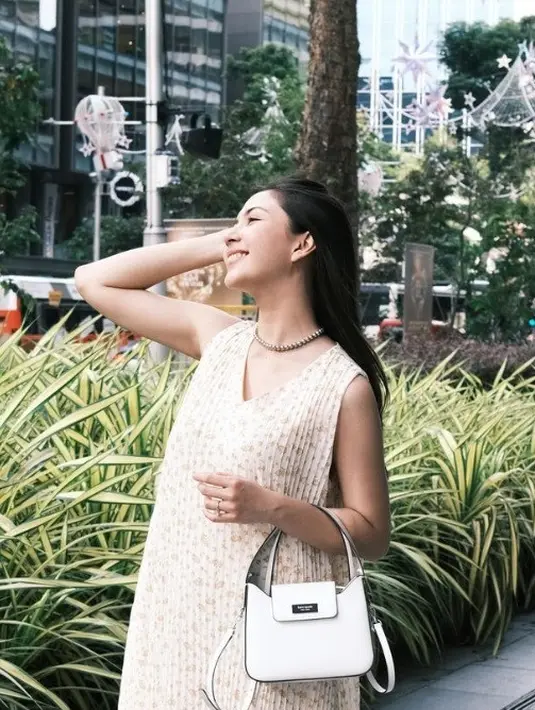 Jessica Mila memadukan penampilannya dengan tas Kate Spade. Ia tampil dengan dress bermotif pleats dan bunga-bunga, sambil memadukannya dengan Sam Icon Mini Hobo berwarna True White. Foto: Document/Kate Spade New York.