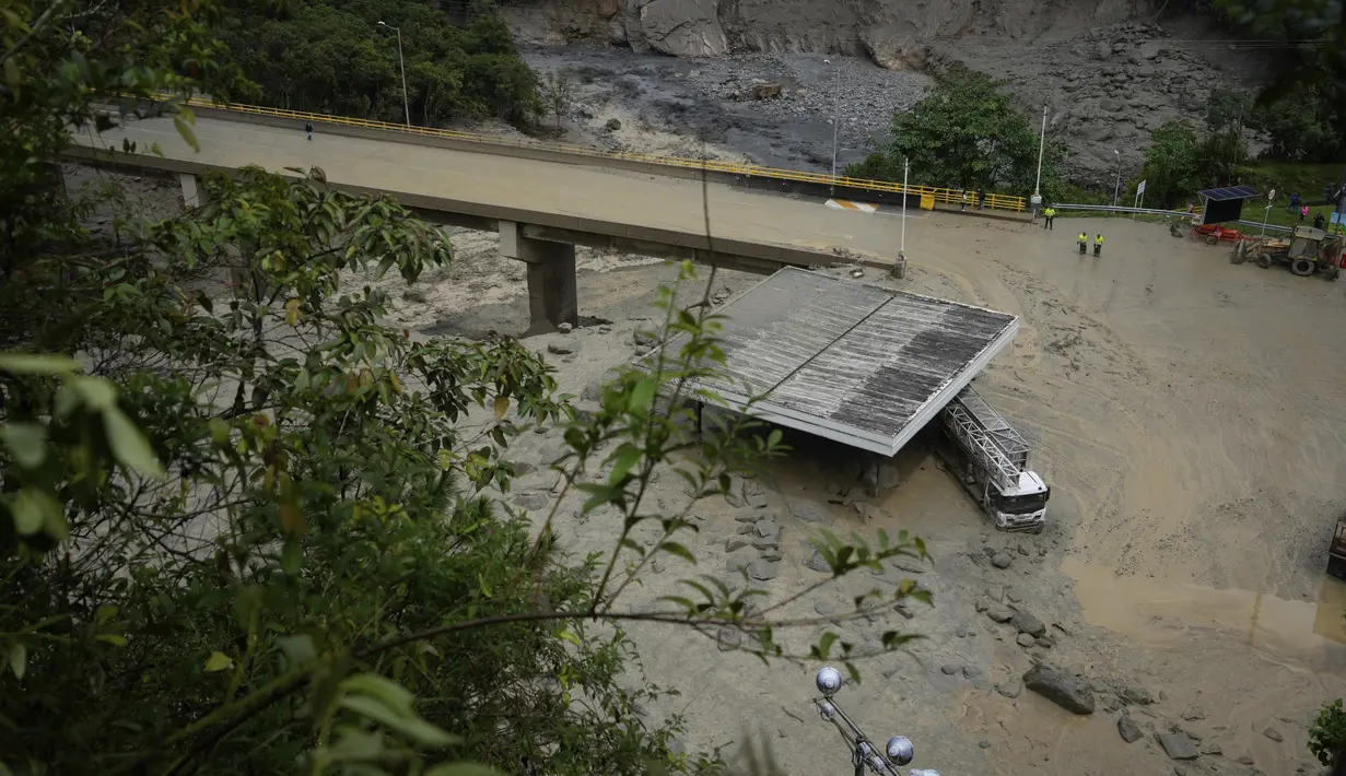 Sebuah truk tertutup lumpur di bawah jembatan yang ambruk saat longsoran maut yang juga melanda beberapa rumah di El Naranjal, Kolombia, Selasa, 18 Juli 2023. (AP Photo/Fernando Vergara)