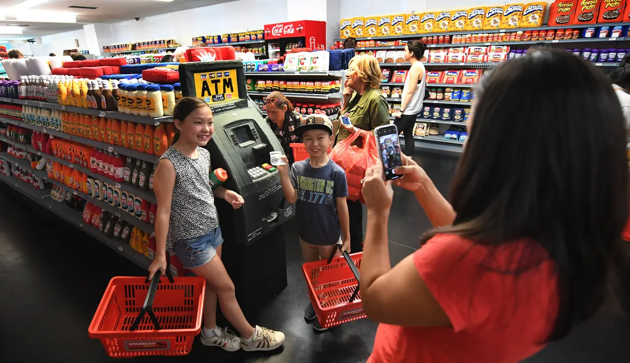 Anak-anak berpose dengan ATM pada instalasi seni berjudul 'Sparrow Mart Supermarket' di hotel The Standard, Los Angeles, 10 Agustus 2018. Sparrow Mart dilengkapi lemari rak, freezer dan bahkan ATM yang semuanya terbuat dari kain felt. (MARK RALSTON/AFP)