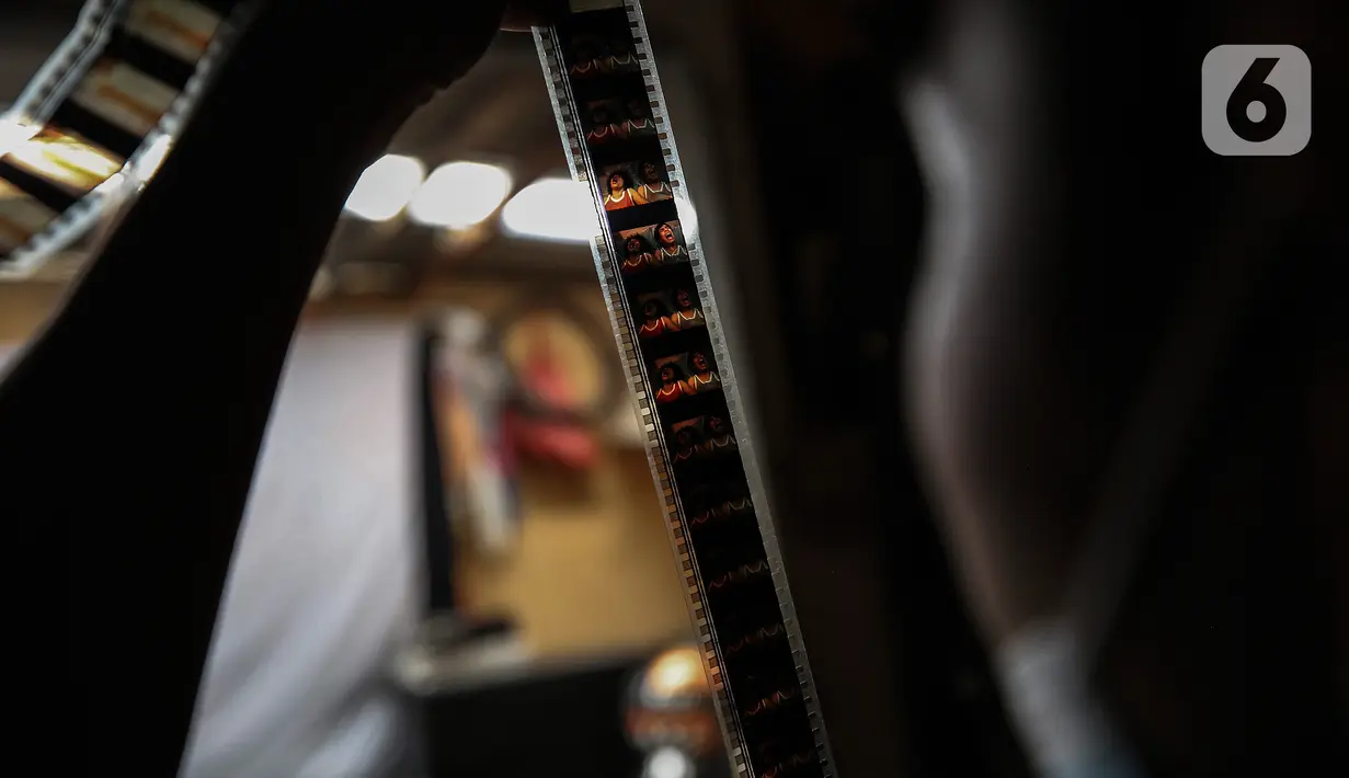 Adul (29) mengecek film seluloid 35mm untuk pertunjukan layar tancap di gudang rumahnya di Jakarta, Rabu (28/4/2021). Saat ini Adul dan ayahnya hanya bisa merawat peralatan dan film seluloid 35mm di gudang rumah mereka. (Liputan6.com/Johan Tallo)