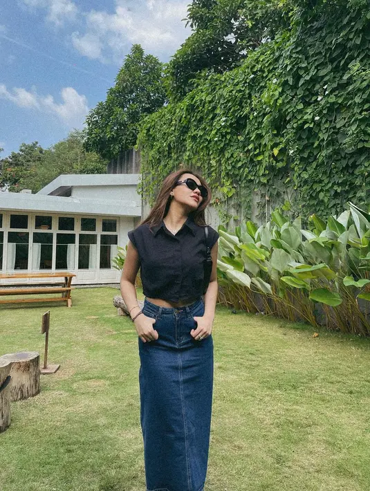 Gaya kasual yang kekinian dengan padu padan crop shirt warna hitam dan rok pencil denim. Makin kece dengan kacamata hitam. [@aaliyah.massaid].
