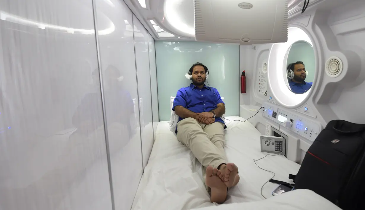Seorang pengunjung menonton televisi di dalam Hotel Urbanpod di Mumbai, India (14/4). Urbanpod ini menyediakan 140 ruangan dengan berbagai macam kategori, seperti Suite Pods, Private Pods, dan exclusive Pods. (AFP/Indranil Mukherjee)