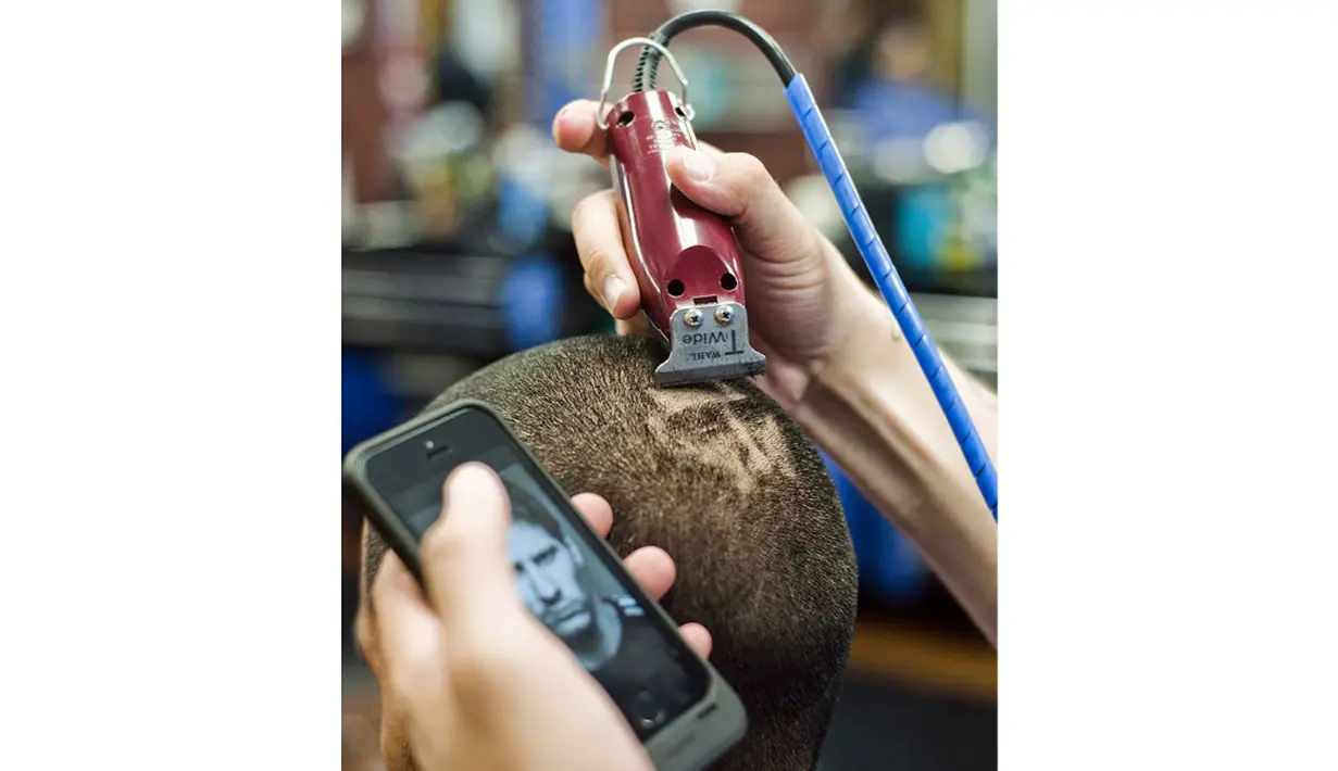 Dengan sangat hati-hati, Rob Ferrel, berusaha merapikan lukisan bergambar wajah Lionel Messi di rambut pelanggannya di San Antonio, Texas, (30/6/2014). (REUTERS/Ashley Landis)