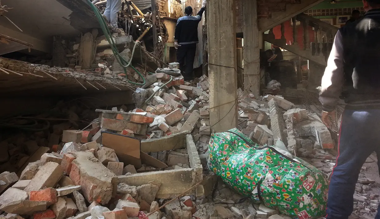 Sejumlah orang mengevakuasi barang yang masih bisa diselamatkan dari sebuah bangunan yang rusak di Imphal pasca gempa 6,7 SR yang mengguncang timur laut India, Senin (4/1). Delapan orang tewas dan lebih dari 100 luka-luka akibat gempa. (AFP PHOTO/STR)