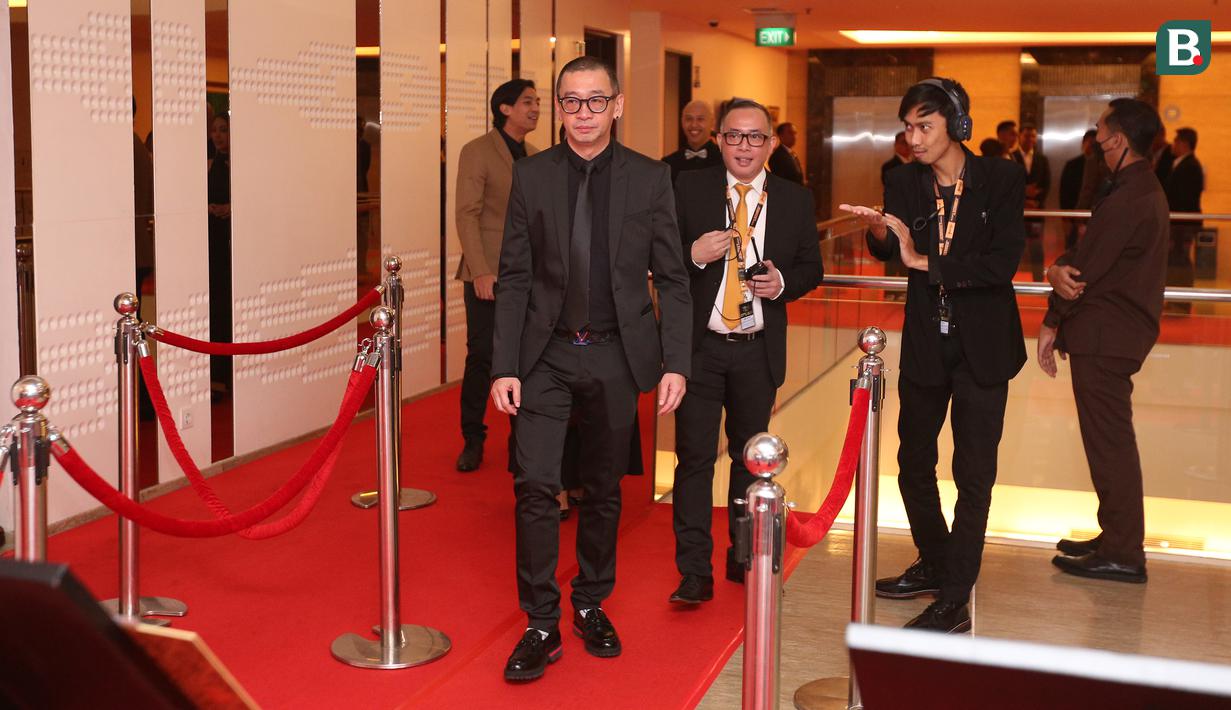 Mantan pelatih Timnas Futsal Indonesia, Justinus Lhaksana berjalan di atas karpet merah pada sebuah acara yang berlangsung di Hotel JS Luwansa, Kuningan, Jakarta, Rabu (19/07/2023). Coach Justin terlihat mengenakan jas hitam dipadukan dengan kemeja dan dasi yang juga berwarna hitam. (Bola.com/Bagaskara Lazuardi)