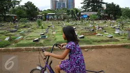 Seorang anak bermain sepeda di sekitar TPU Karet Bivak, Jakarta, Jumat (13/1). Semakin berkurangnya lahan hijau menyebabkan anak-anak di Ibukota terpaksa bermain di tempat yang tidak semestinya. (Liputan6.com/Immanuel Antonius)