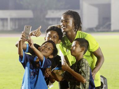 Fans cilik foto bersama dengan pemain Timnas  Indonesia U-19, Ronaldo Kwateh, usai melakukan latihan jelang Piala AFF U-19 2022 di Stadion Madya, Jakarta, Selasa (21/6/2022). (Bola.com/M Iqbal Ichsan)