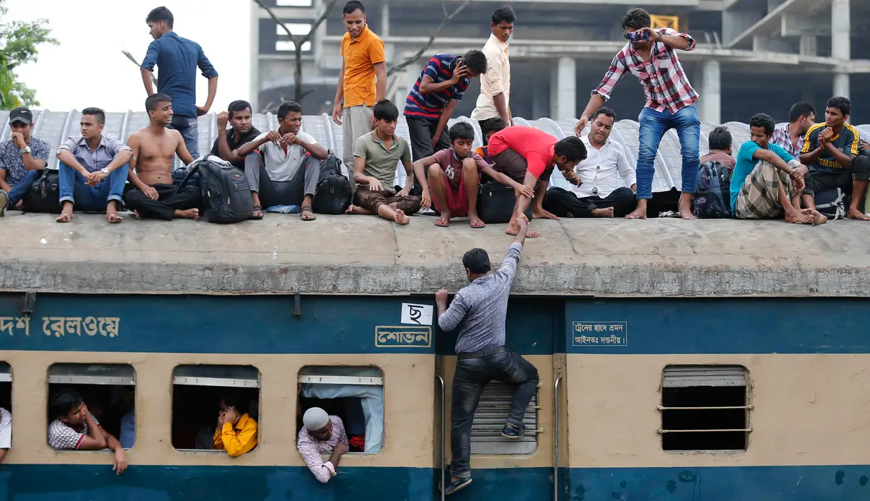 Seorang penumpang berusaha naik ke atap kereta api saat akan pulang kampung di stasiun kereta api di Dhaka, Bangladesh, (22/6). Ribuan yang bekerja di Dhaka pulang ke kampung halamannya untuk merayakan lebaran bersama keluarganya. (AP Photo/A.M.Ahad)