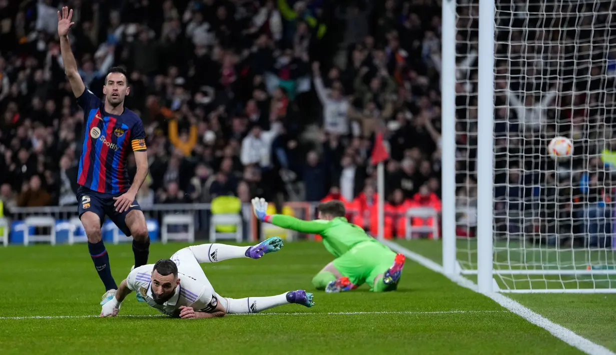 Pemain Barcelona Sergio Busquets (kiri) memberi isyarat setelah pemain Real Madrid Karim Benzema (tengah) mencetak gol offside pada pertandingan sepak bola leg pertama semifinal Copa del Rey di Stadion Santiago Bernabeu, Madrid, Spanyol, 2 Maret 2023. Barcelona sukses megalahkan Real Madrid dengan skor 1-0 berkat gol bunuh diri Eder Militao. (AP Photo/Bernat Armangue)
