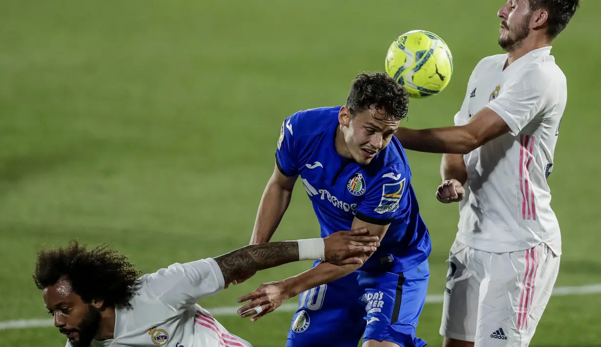 Pemain Real Madrid, Victor Chust, duel udara dengan pemain  Getafe, Enes Unal, pada laga Liga Spanyol di Stadion Alfonso Perez, Senin (19/4/2021). Kedua tim bermain imbang 0-0. (AP Photo/Manu Fernandez)