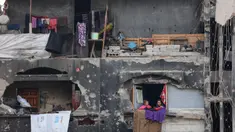 Anak-anak perempuan Palestina yang mengungsi melihat keluar rumah yang rusak tempat mereka berlindung di Beit Lahia di Jalur Gaza utara, menjelang waktu berbuka puasa selama bulan suci Ramadan pada 9 Maret 2025. (Omar AL-QATTAA/AFP)