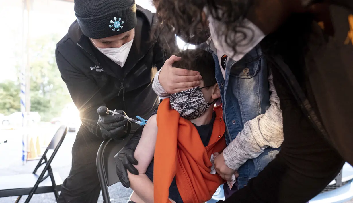 Levi Lefkove (6) dipegang oleh saudara perempuannya Leah (9) saat mendapatkan vaksin COVID-19 pada hari pertama vaksinasi untuk anak 5 - 11 tahun di Decatur, Georgia, Rabu (3/11/2021). Ini menjadi langkah perdana vaksinasi Covid-19 bagi anak kecil di Amerika Serikat. (AP Photo/Ben Gray)
