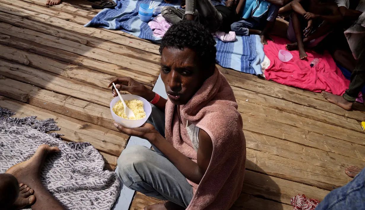 Seorang migran makan di geladak kapal penjaga pantai LSM Open Arms Spanyol setelah diselamatkan dari perairan terbuka selama operasi penyelamatan di zona perairan internasional di laut Mediterania, Rabu, 21 September 2022. (AP/Petros Karadjias)
