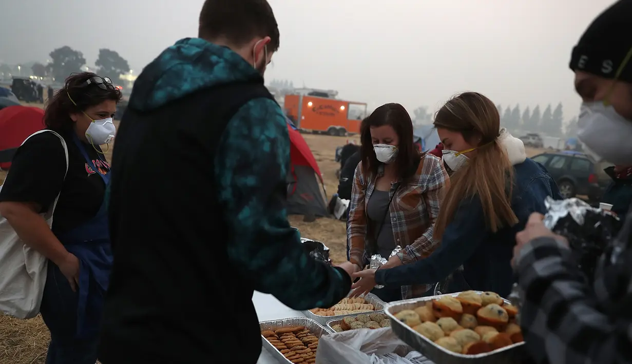 Pengungsi mengambil kue di pusat pengungsian di tempat parkir Walmar, Chico, California (16/11). Departemen Kehutanan dan Perlindungan Kebakaran California mengatakan api telah menghancurkan 40 persen Kota Paradise. (AFP Photo/Justin Sullivan)