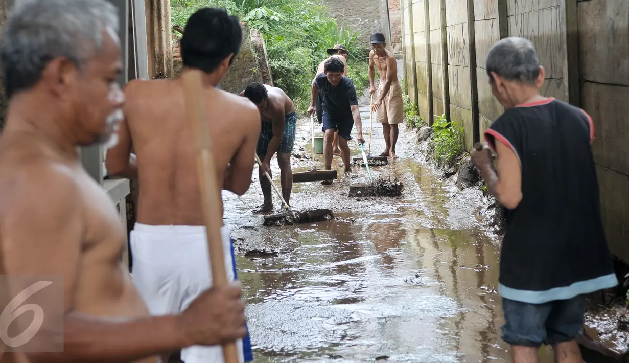 Warga bergotong royong membersihkan lumpur sisa banjir yang menutup jalan, Jakarta, Senin (7/11). Sebelumnya, ratusan rumah warga di RW 02 Cawang, Kramat Jati, Jakarta Timur tergenang akibat banjir kiriman dari kawasan Bogor. (Liputan6.com/Yoppy Renato)