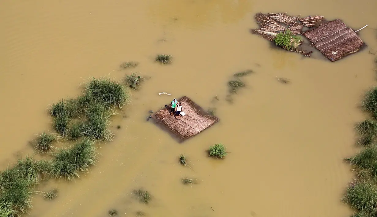 Warga bertahan di atap rumah yang terendam banjir sambil menunggu bantuan paket makanan yang didistribusikan oleh helikopter Angkatan Udara India di pinggiran Allahabad, India, Kamis (25/08). (REUTERS / Jitendra Prakash)