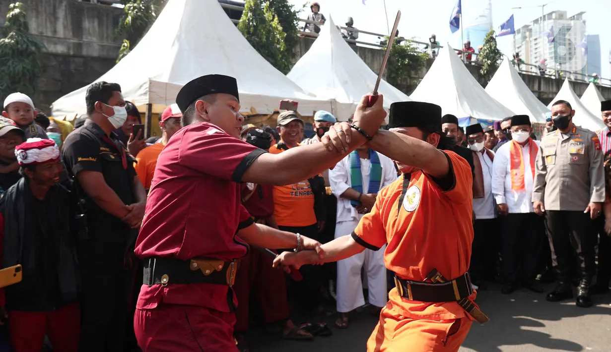 Dua warga beradu saat menampilkan pertunjukan kesenian bela diri asli Betawi Palang Pintu dalam Lebaran Tenabang 2022 di kawasan Tanah Abang, Jakarta, Sabtu (4/6/2022). Kegiatan yang menampilkan berbagai kesenian Betawi, makanan tradisional, perlombaan, dan bazar UMKM itu mengangkat tema KolaborAksi. (Liputan6.com/Angga Yuniar)
