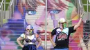 Kristina Broclebanl dan Max Avatar Barnett yang merupakan penggemar Taylor Swift berpose dengan potret Swift yang dilukis di tangga Stadion Wembley menjelang rangkaian konser The Eras Tour di London, Rabu (14/8/2024). (AP Photo/Alastair Grant)