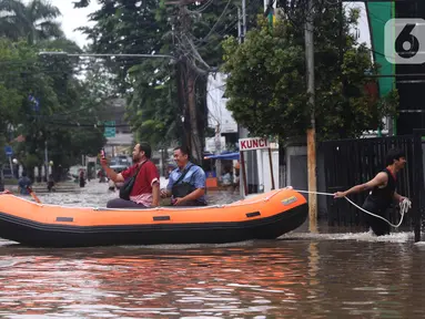 Warga menaiki perahu karet melintasi banjir yang merendam kawasan Benhil, Jakarta, Selasa (25/2/2020). Hujan yang mengguyur wilayah tersebut membuat air sungai meluap sehingga menyebabkan Banjir setinggi pinggang orang dewasa. (Liputan6.com/Angga Yuniar)