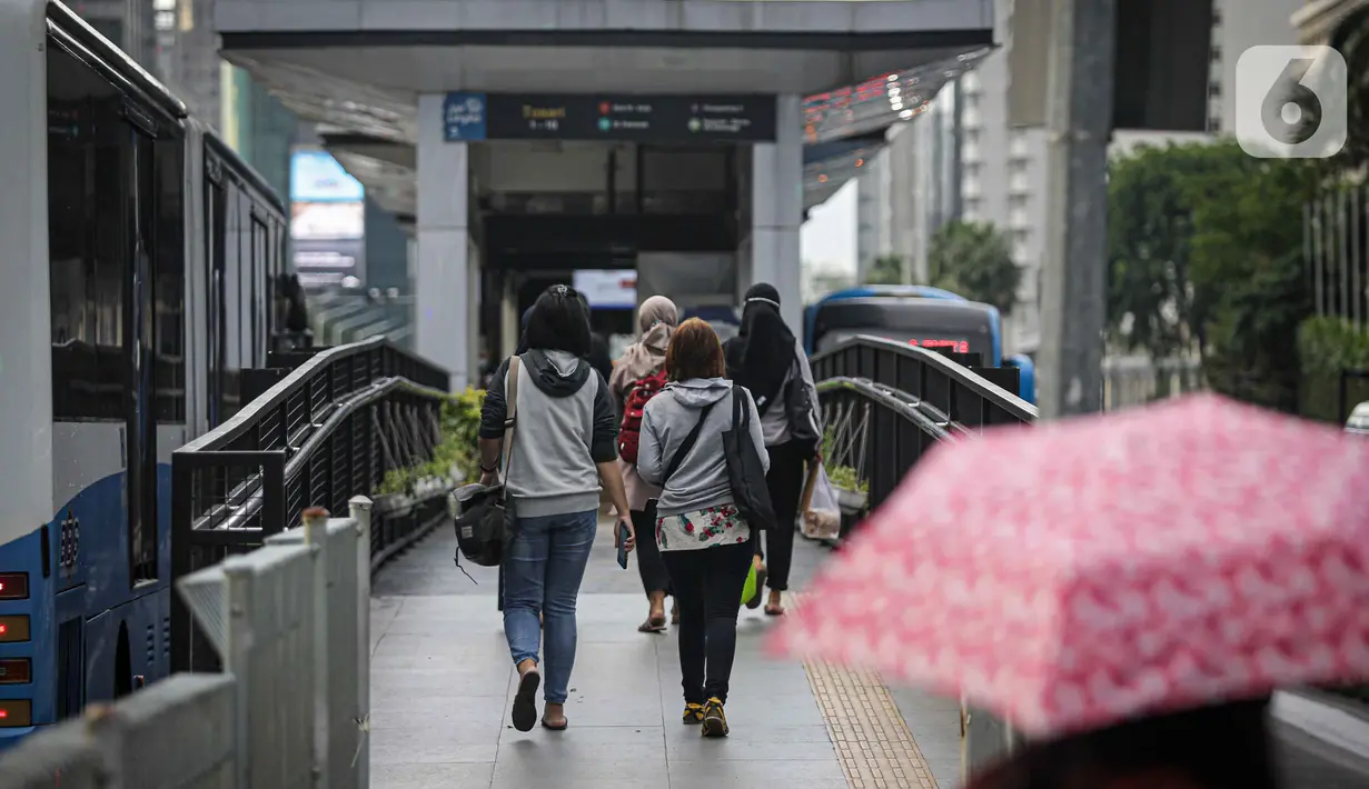 Sejumlah pekerja berjalan menuju halte di kawasan Jalan Sudirman, Jakarta, Selasa (2/11/2021). Sektor non-esensial kini boleh mempekerjakan hingga 75 persen karyawannya dari kantor. Sebelumnya, angka ini dibatasi hingga 50 persen. (Liputan6.com/Faizal Fanani)