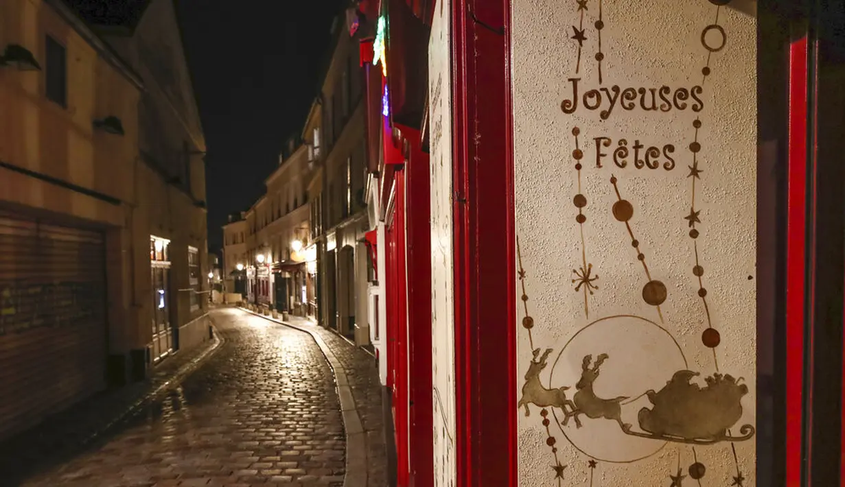Sebuah plakat bertuliskan "Selamat Liburan" terlihat pada jalan yang kosong selama jam malam di Montmartre, Paris, Perancis, Selasa (15/12/2020). Jam malam berlaku pada pukul 20.00 hingga 06.00. (AP Photo/Michel Euler)