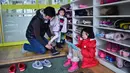 Kim Jin-Sung memakaikan sepatu anaknya Won-Woo di perawatan anak di Seoul. Kim adalah salah satu dari meningkatnya jumlah ayah di Korea Selatan memilih istirahat dari karirnya untuk membantu membesarkan anak-anaknya. (AFP PHOTO/JU)