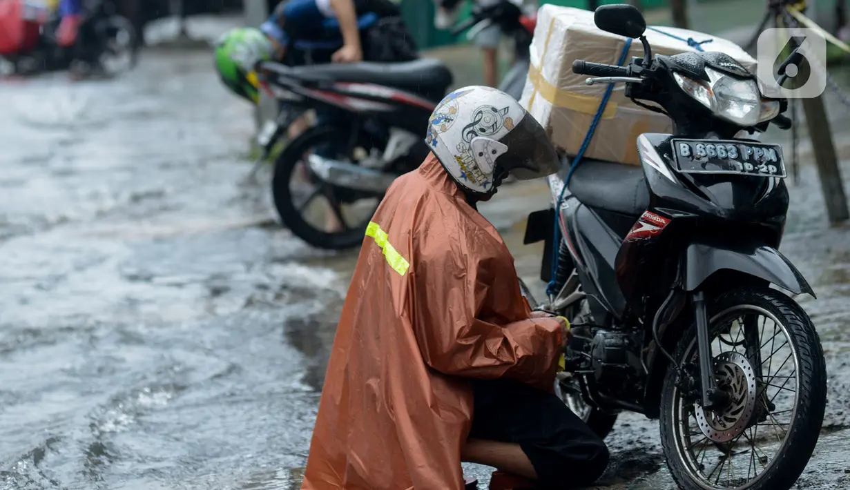 Pengendara mengecek sepeda motornya setelah menerjang genangan air di Jalan Sukarjo Wiryopranoto, Jakarta, Jumat (24/1/2020). Hujan deras yang mengguyur Jakarta sejak pagi tadi mengakibatkan Jalan Sukarjo Wiryopranoto tergenang air sekitar 30 cm. (merdeka.com/Imam Buhori)