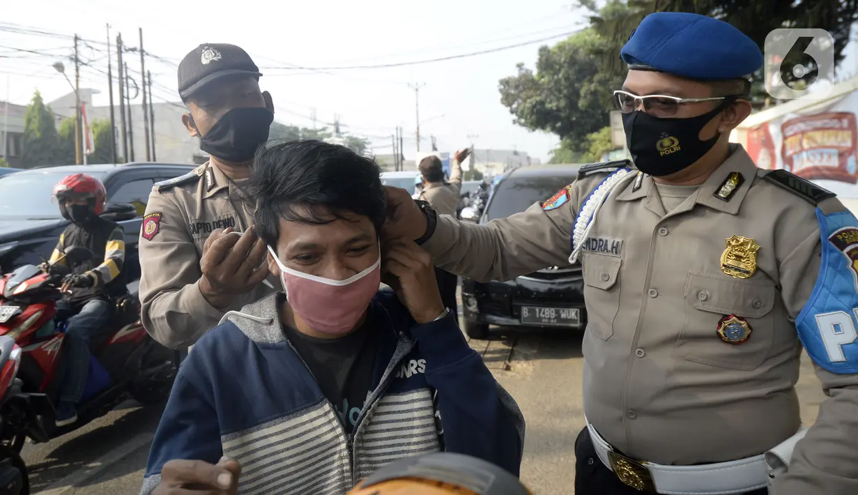 Anggota polisi dari Polsek Parung membantu memasangkan masker kepada pengendara sepeda motor di depan Polsek Parung, Kabupaten Bogor, Jawa Barat, Rabu (2/9/2020). Pembagian masker gratis setiap usai apel ini inisiatif anggota sejak masa pandemi COVID-19. (merdeka.com/Dwi Narwoko)